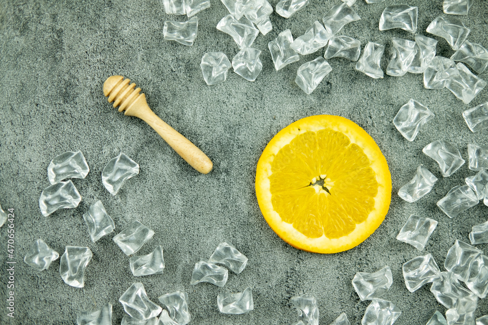 Wooden honey stick and slices of orange placed with piece iced artificial crystal Wooden honey stick and slices of orange placed with piece iced artificial crystal