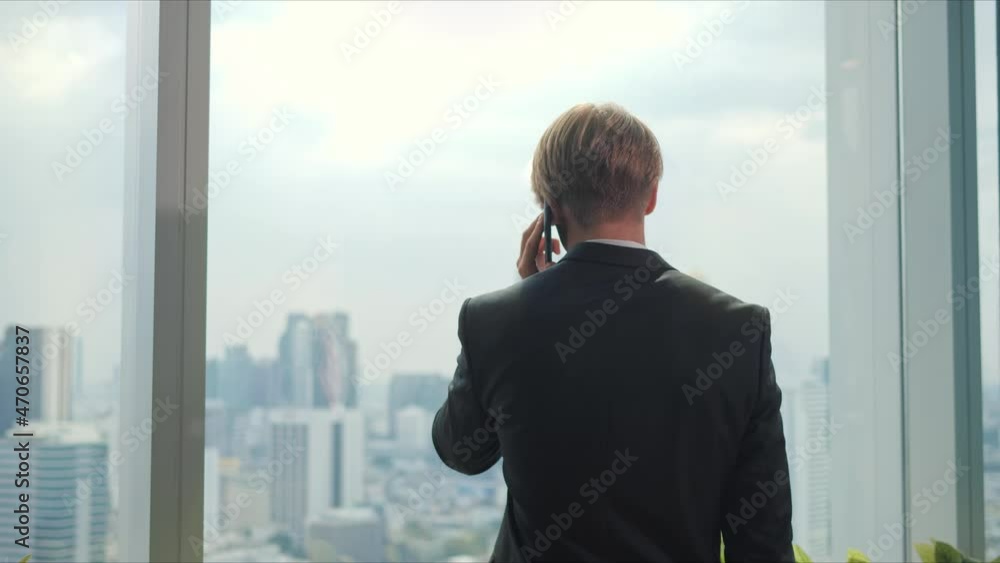 A young businessman stands and speaks on the phone. He is dedicated to his work. A young businessman stands and speaks on the phone. He is dedicated to his work.