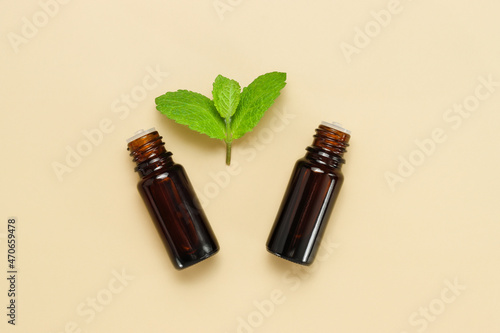 Top view mockup bottle with essence or body oil with fresh green plant leaf  delicate beige background