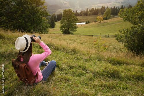 Young woman with binoculars in nature, space for text