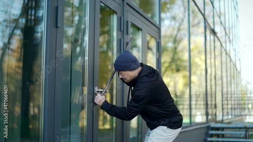 A thief burglar broke the open door of a house or office by breaking into the middle. The bandit sneaks into the building. intruder trying to force a door lock using a crowbar