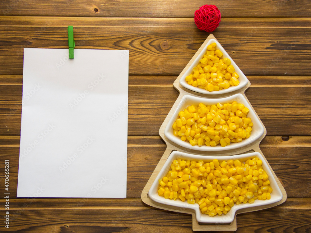 Happy New Year 2022. New Year's yellow corn in saucers in the form of a Christmas tree. Christmas wooden background with white numbers 2022 Happy New Year 2022. New Year's yellow corn in saucers in the form of a Christmas tree. Christmas wooden background with white numbers 2022