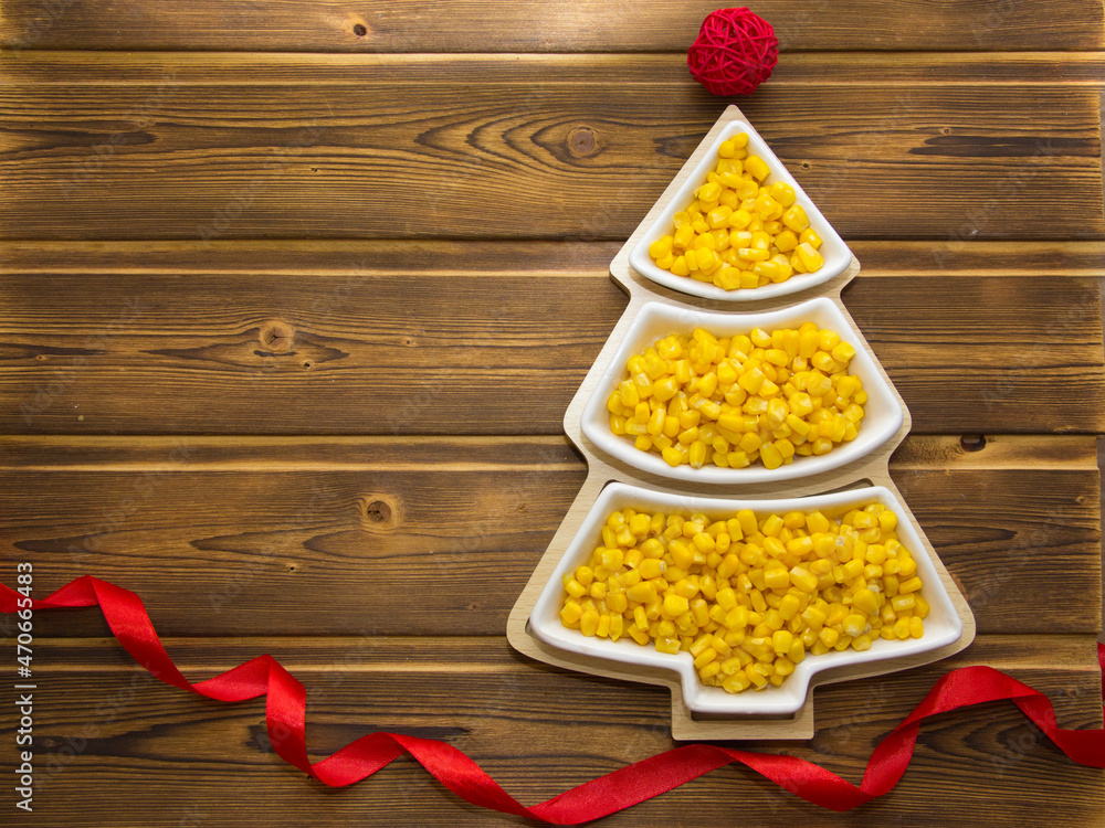 Happy New Year 2022. New Year's yellow corn in saucers in the form of a Christmas tree. Christmas wooden background with white numbers 2022 Happy New Year 2022. New Year's yellow corn in saucers in the form of a Christmas tree. Christmas wooden background with white numbers 2022