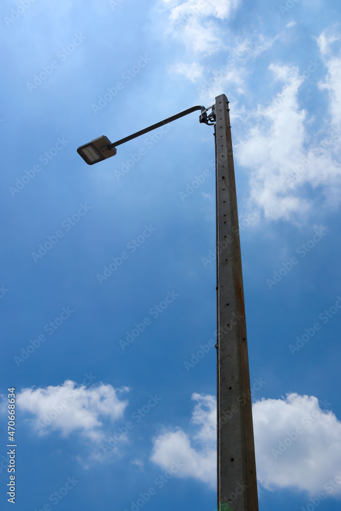LED street lamps are mounted on tall concrete light poles with background of the sky.