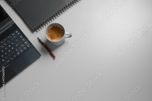 laptop on a desk with dark paper and pen and  a cup of coffee