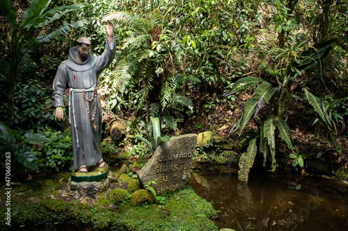 Photography image of patron saint in grotto with green plants in the upper mountain