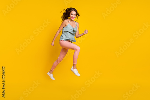 Full size photo of positive cheerful woman jump up run look empty space sale news isolated on yellow color background