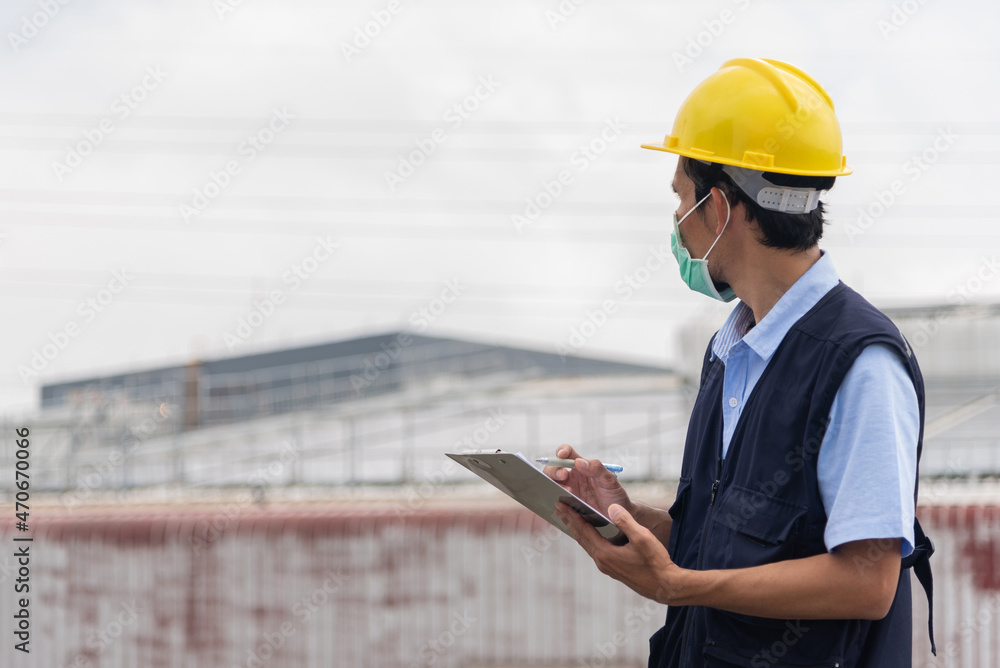 Worker with clipboard at factory building background