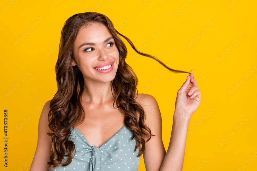 Photo of young attractive woman happy positive smile hold hair tails curious look empty space isolated over yellow color background Photo of young attractive woman happy positive smile hold hair tails curious look empty space isolated over yellow color background