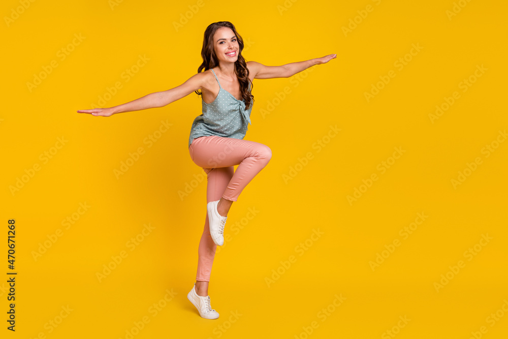 Full body profile side photo of young attractive woman happy positive smile hands wings air fly isolated over yellow color background Full body profile side photo of young attractive woman happy positive smile hands wings air fly isolated over yellow color background
