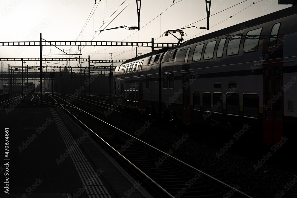 Obraz premium Brouillard dans la gare de Romont en Suisse, photo en contre jour avec les voies et les poteaux.