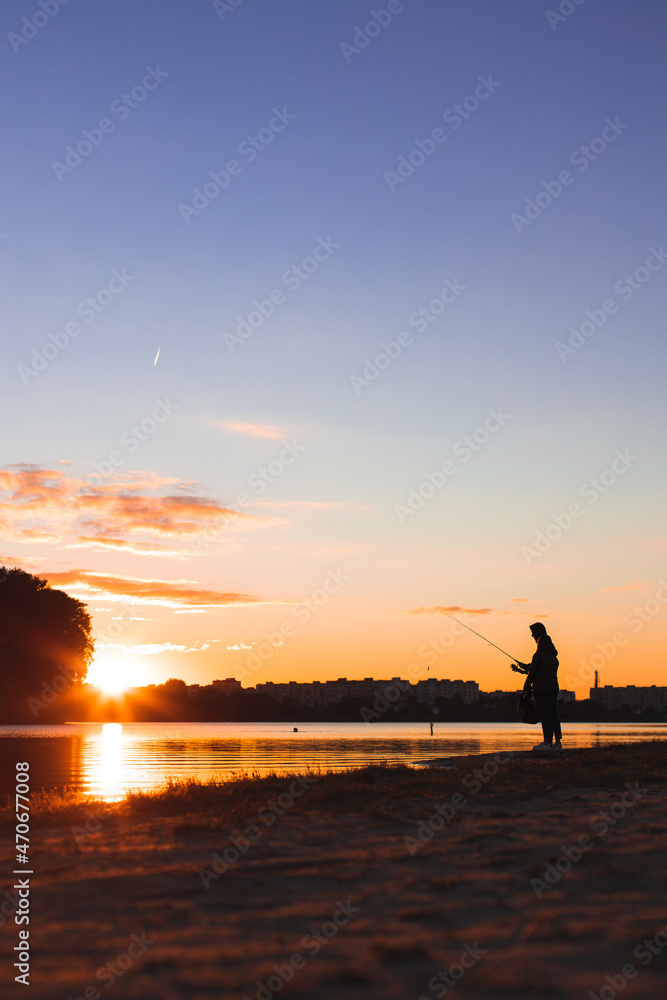 river shore line fishing person solitude atmosphere weekend activity beautiful picturesque sunset evening light, vertical photography, unfocused silhouette concept of the humans