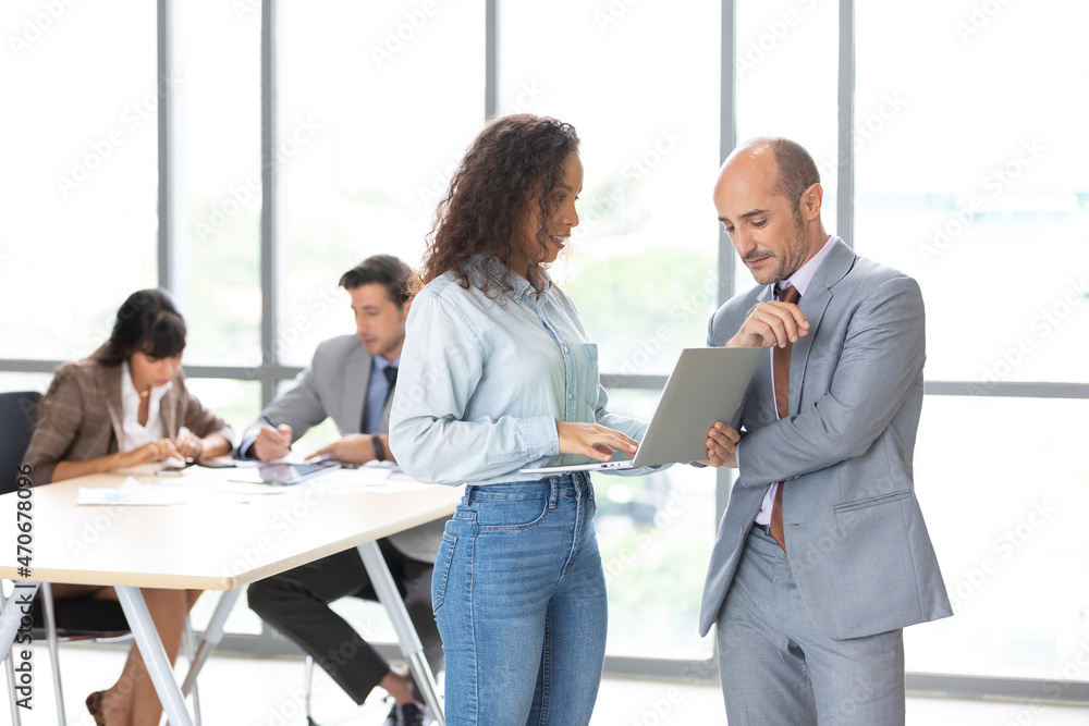 businesswoman and businessman using laptop computer and talking about work or project in office businesswoman and businessman using laptop computer and talking about work or project in office