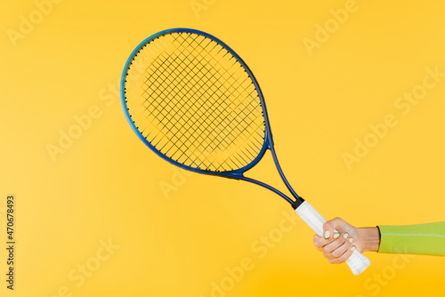 cropped view of sportswoman holding tennis racquet isolated on yellow © LIGHTFIELD STUDIOS