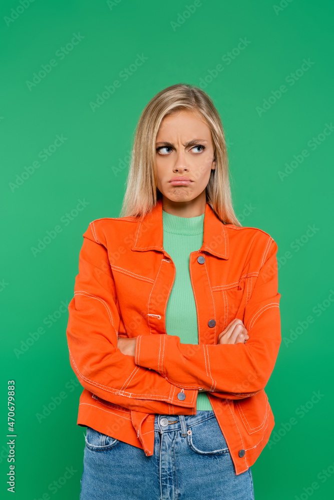offended woman frowning and pouting lips while standing with crossed arms isolated on green offended woman frowning and pouting lips while standing with crossed arms isolated on green