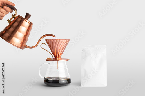 Blank coffee packaging container with a copper pot pouring coffee into dripper, front view, coffee packaging mockup with empty space to display your branding design. photo