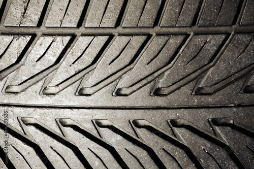 Used rubber tyre texture. Junkyard closeup dumped car wheel. Tire tread pattern. Black shiny rubber auto tyre backdrop.