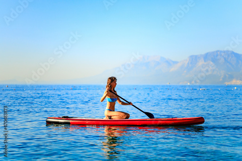 Woman sitting on sup board and enjoying peace and quiet outdoors