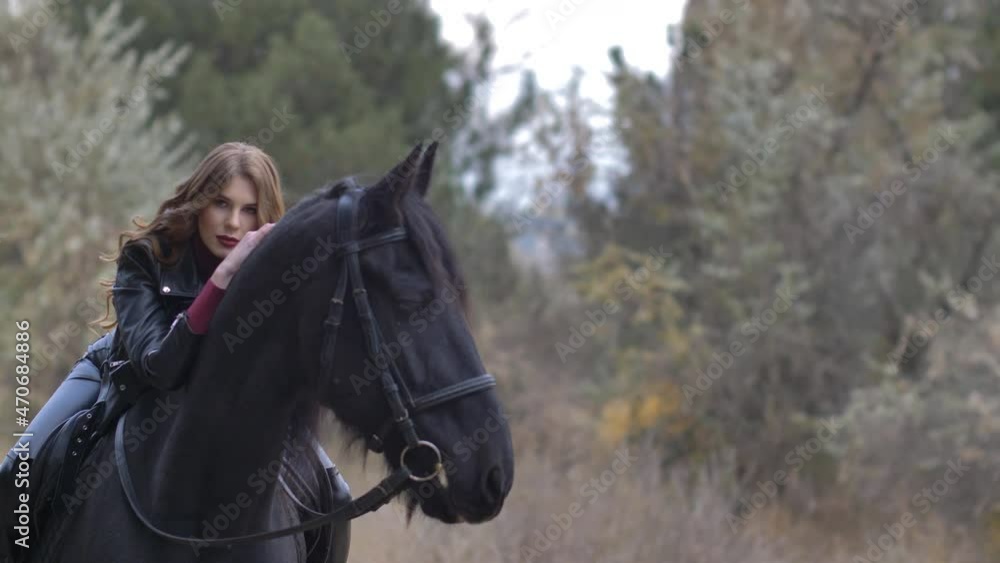 Beautiful young woman sitting astride hugs a horse and posing outdoors