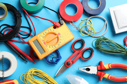 Flat lay composition with electrician's tools and accessories on light blue background