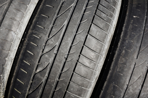 Used rubber tyre texture. Hazard to use vehicle wheel. Risk of explosion. Junkyard closeup dumped car wheel. Tire tread pattern. Cracked dangerous rubber auto tyre backdrop.