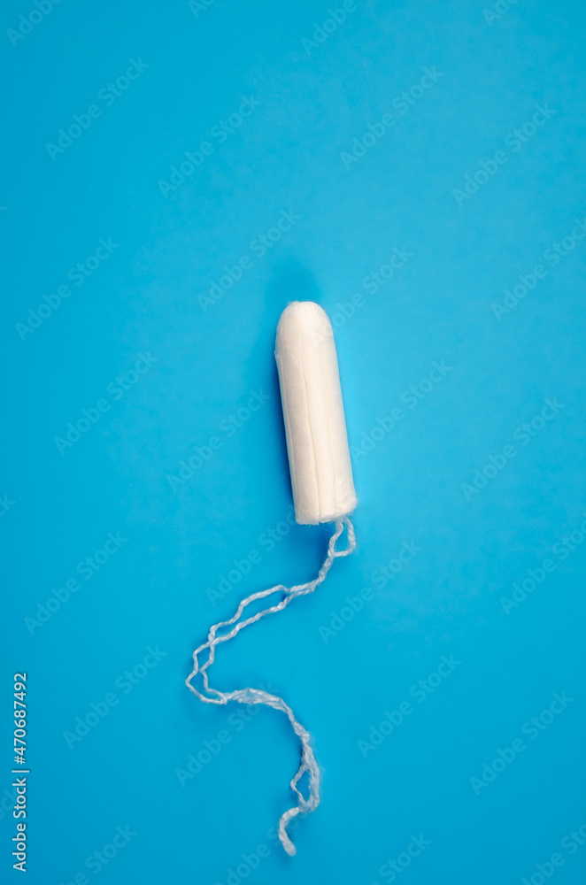 One hygienic feminine tampon on blue background. tampon for women, protection during menstruation. One hygienic feminine tampon on blue background. tampon for women, protection during menstruation.