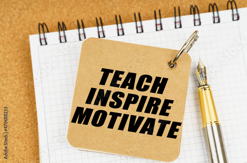 There are two notebooks and a pen on the table. On the top notepad, the inscription - Teach Inspire Motivate photo