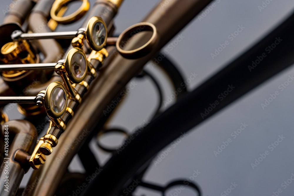 Fototapeta premium A rotary type trumpet with a curved leadpipe in matte brown with gold elements and pearl type buttons on a reflective surface