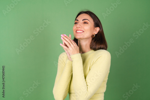 Young woman on a green background in a yellow sweater cute smiling