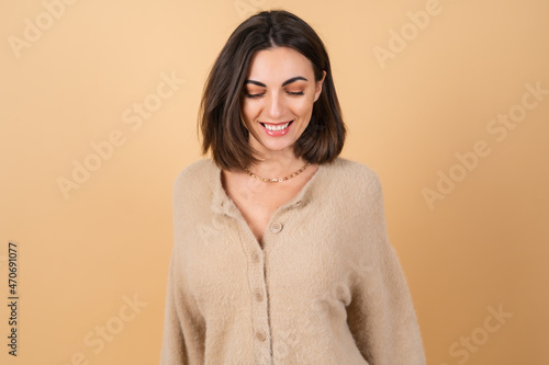 Canvastavla Young woman on a beige background in a soft cozy sweater with daytime profession
