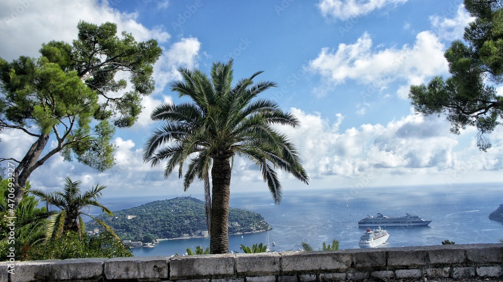 Cote d'Azur, France, September 2010, palm trees on the embankment, an island and a large white ship are visible in the sea