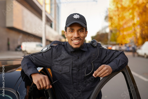 Police officer in uniform poses at the patrol car