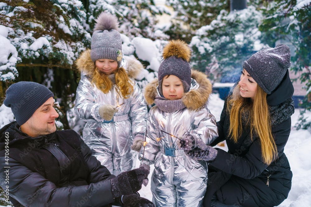 Attractive family having fun in winter park. Parents spend time outdoors with children playing together
