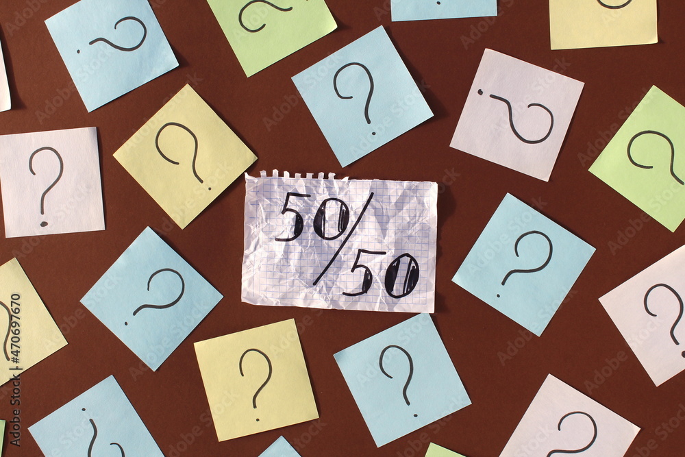 On a white squared notebook paper, it says 50-50, surrounded by sprinkling signs. On a white squared notebook paper, it says 50-50, surrounded by sprinkling signs.