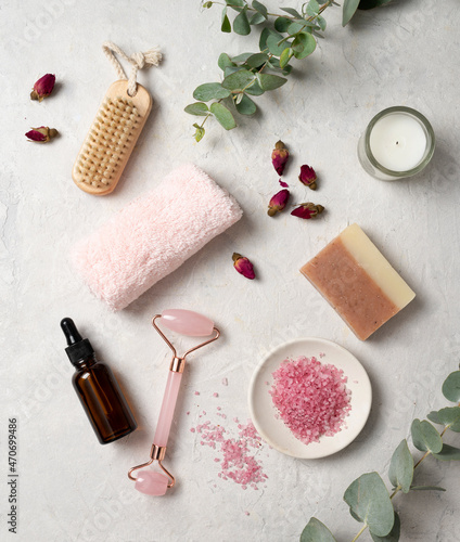 Organic pink sea salt with rose, massage oil, soap, towel and a wooden brush on a white textured background. The concept of spa and wellness. Top view