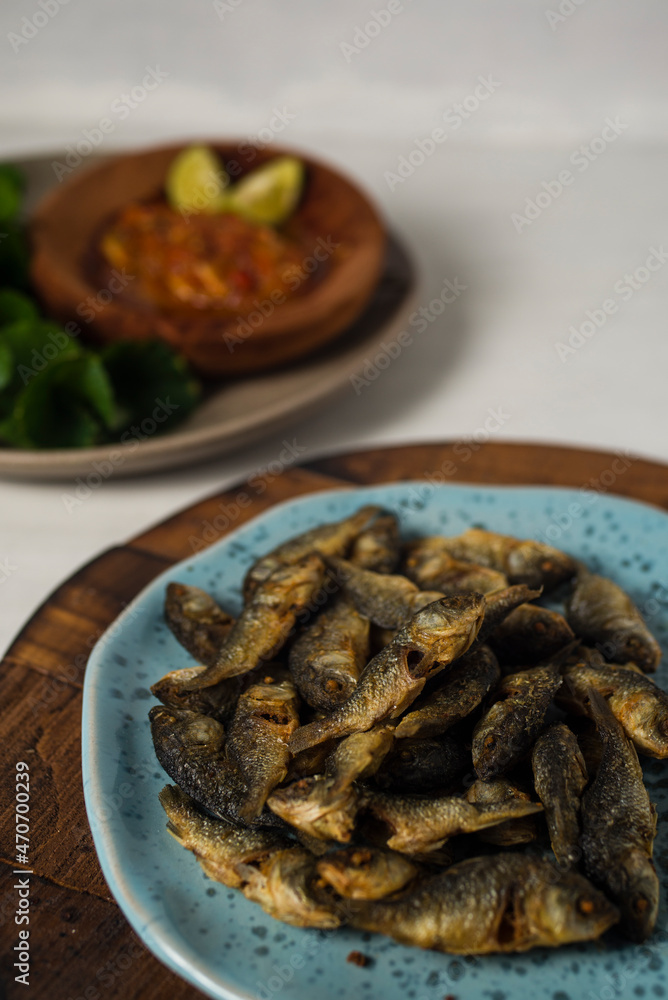 fried baby fish with hot and spicy sauce and cantella asiatica as side dish on wooden board against white background