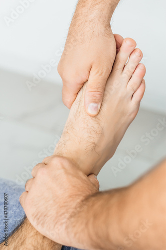Osteopath working with ankle, examines a man's foot, close-up