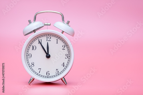 a white retro clock on a pink background shows 23.55