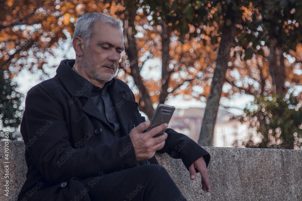 man in coat sitting using mobile phone man in coat sitting using mobile phone