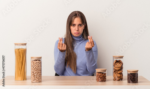 Young caucasian woman sitting at a table with food pot isolated on white background showing that she has no money.