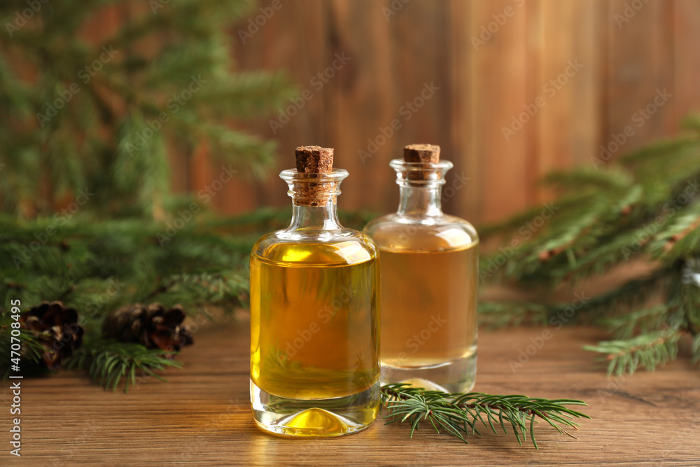 Bottles with pine essential oil on wooden table Bottles with pine essential oil on wooden table