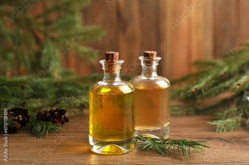 Bottles with pine essential oil on wooden table