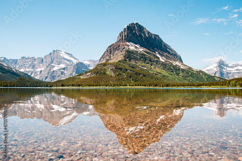 A snowy mountain water reflection on Swiftcurrent Lake in Many Glacier region of Glacier National Park, Montana. Grinnell Point, a subpeak of Mount Grinnell is part of Lewis Range in Babb, Montana. photo