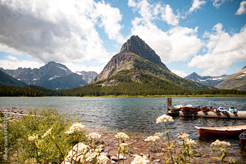 Mountain Peak Landscape Scene of Grinnell Point and Swiftcurrent Lake in Glacier National park. Boats docked in the water with a vibrant blue sky above. photo