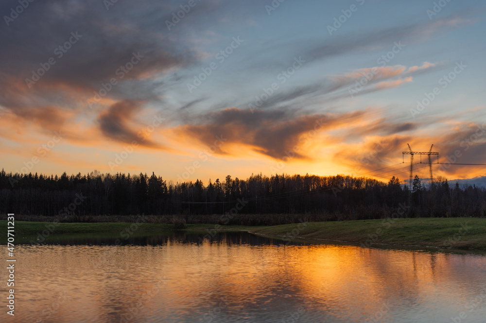 reflections of colored clouds in the lake water at sunset,silhouettes of trees in golden hour