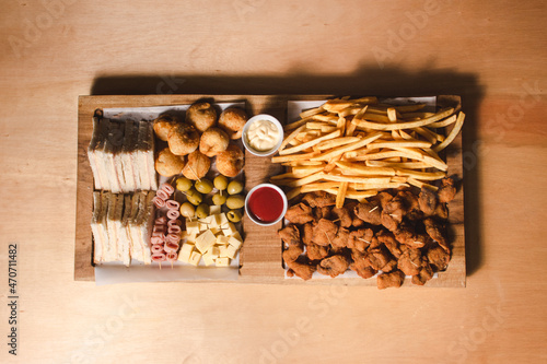 Top view of a variety of picadas with condiments on top of a large wooden board. photo