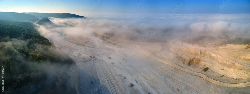 Aerial view of open pit mining site of limestone materials extraction for construction industry with excavators and dump trucks