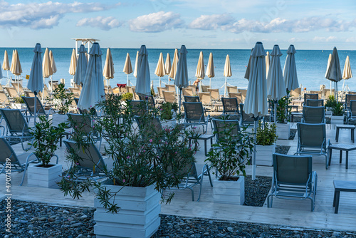 many sun loungers and umbrellas on a wooden platform on a sandy beach by the sea in the resort town of Sochi  Russia