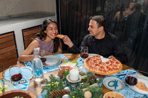 man feeding his partner pizza in his mouth during christmas dinner