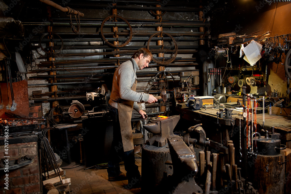 Blacksmith working metal with hammer on the anvil in the forge Blacksmith working metal with hammer on the anvil in the forge